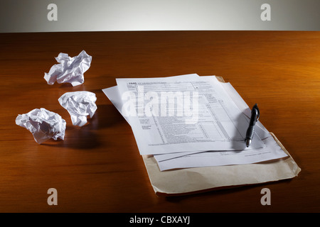 Crumpled paper and tax form on desk Stock Photo