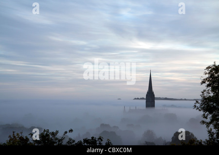 The spire of Salisbury Cathedral emerges from layers of mist on an October morning. Stock Photo