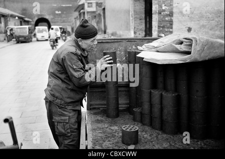 Pingyao, China. Man delivering coal briquettes, used for heating and cooking, to a household. Stock Photo