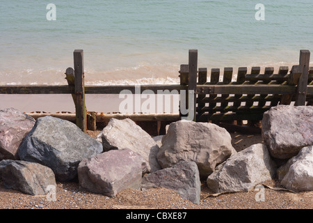 Happisburgh beach. Norfolk. East Anglia. Remains of sea damaged timber breakwater with imported granite rocks, foreground. Stock Photo