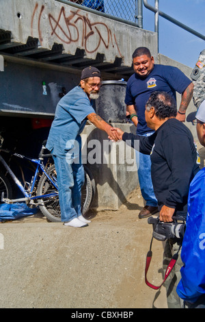 An official of the charitable outreach program Vet Hunters greets a homeless military veteran living under a California bridge. Stock Photo