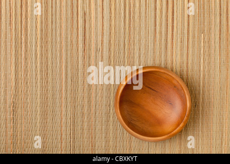 a small empty wooden bowl on grass mat Stock Photo