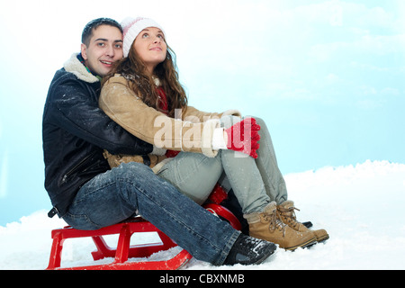 Portrait of happy couple sitting on sledge in winter Stock Photo