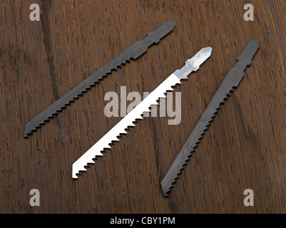 Metal and wood jigsaw blades on a wooden block Stock Photo