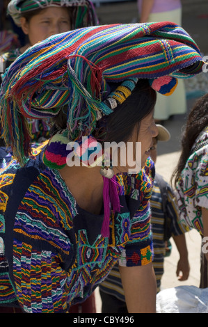 An indigenous Central American Indian woman in Guatemala wearing traditional woven clothing and with hair braiding and pom-poms. Stock Photo