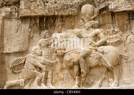 This stone relief at Naqsh-e Rostam near Persepolis, Iran, shows the Persian emperor Shapur triumphing over two Roman emperors. Stock Photo