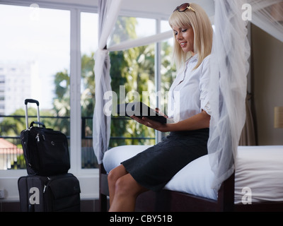 Mid adult caucasian businesswoman typing on tablet pc in hotel room during business travel. Side view, three quarter length Stock Photo