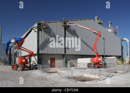 2 men working in cherry pickers on a new industrial unit Stock Photo