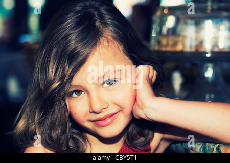 Cute portrait of a young 5 year old brunette girl smiling with big brown eyes gazing into the camera. Stock Photo