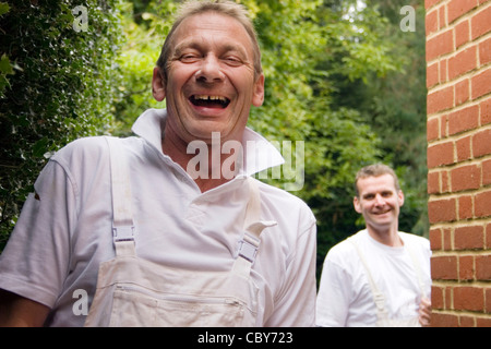 portrait two happy labourers wearing overalls to paint and decorate property Stock Photo