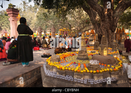 India, Bihar, Bodhgaya, Mahabodhi Temple, pilgrims praying amongst floral offerings in inner courtyard Stock Photo