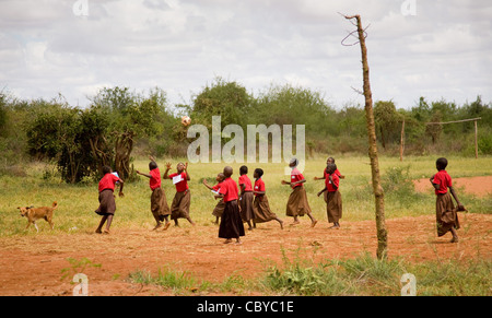 Teenage children playing a game of netball on a school playing field near Voi in southern Kenya while a dog looks on Stock Photo