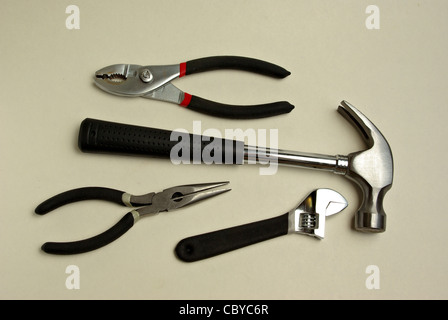 A hammer, needle nose pliers, pliers, adjustable wrench all sit on a white background. Stock Photo