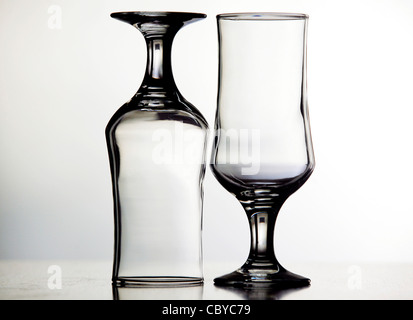 Two glasses, one of them upside down, on a white background Stock Photo