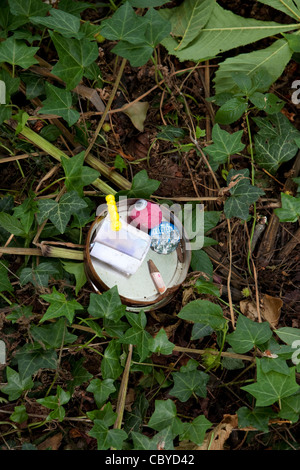 Small open Geocache tin showing its contents Stock Photo