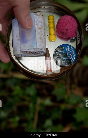 Person showing the contents of a small Geocache tin Stock Photo