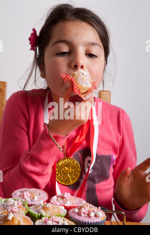 Young girl eating cupcakes alone. Stock Photo