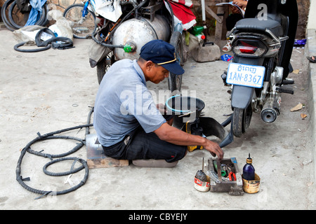 Happy Asian man working in mechanic shop at repairing flat tire, Phnom Penh, Cambodia, Asia Stock Photo