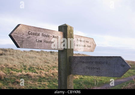 A wooden signpost pointing to Hauxley Nature Reserve, by a public footpath on the Coastal Route in Northumberland, England. Stock Photo