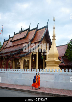 Two orange-clad apprentice Buddhist monks walk by Wat Sen Temple in Luang Prabang, Laos. Stock Photo