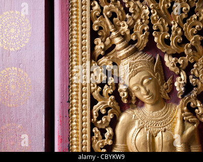 A Buddha on the intricate walls of Wat Xieng Thong in Luang Prabang, Laos. Stock Photo