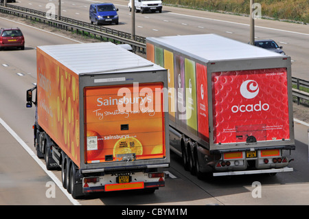 Ocado online grocery supply chain lorry overtaking a Sainsburys supermarket delivery truck business competition on the M25 motorway Essex England UK Stock Photo