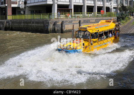 London tourism business amphibious Duck Tours makes big water splash entry into River Thames for tourist people on sightseeing tour in yellow boat UK Stock Photo
