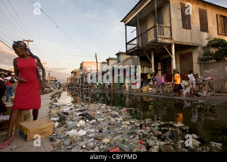 Street scene in Gonaives, Artibonite Department, Haiti, showing an incomplete drainage canal filled with rubbish. Stock Photo