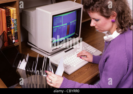 Woman working on old computer doing her household budget looking at floppy disks, retro image Stock Photo