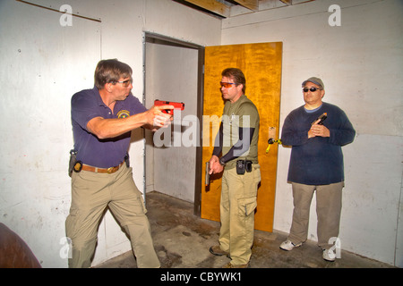 Under the eye of an instructor, law enforcement agents practice entering or 'breaching' a room with weapons. Stock Photo