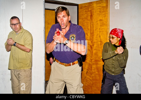 Under the eye of an instructor, law enforcement agents practice entering or 'breaching' a room with weapons. Stock Photo