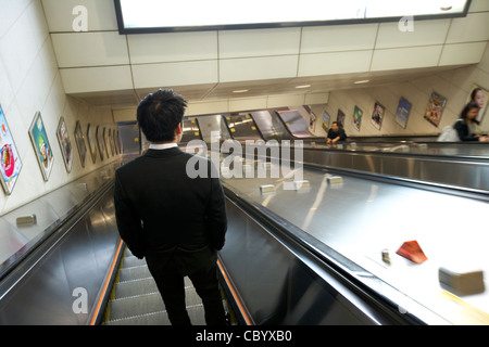 young chinese businessman using down escalator in hong kong mtr public transport system hksar china asia Stock Photo