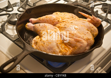 Close up of split whole chicken in frying pan on gas stove. Stock Photo