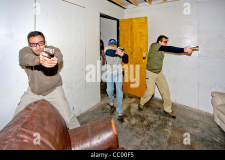 Under the eye of an instructor, law enforcement agents practice entering or 'breaching' a room with weapons. Stock Photo