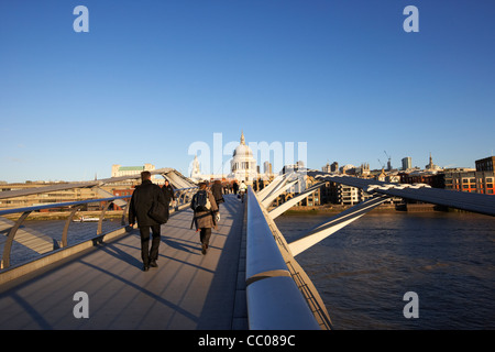 people crossing the millenium footbridge over the river thames in early morning city of London England UK United kingdom Stock Photo