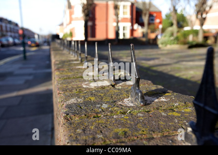 row of painted metal wrought iron spikes to stop people sitting on a garden wall London England UK United kingdom Stock Photo