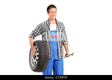 A mechanic holding a spare tire and a wrench Stock Photo