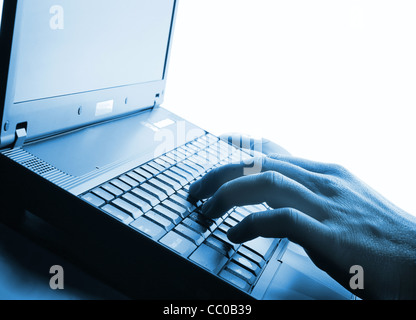 Typing on a laptop, human hand, blue tone Stock Photo