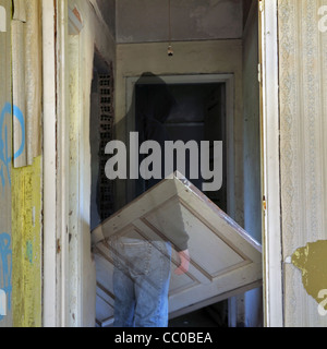 Ghost and unhinged door in the haunted hallway of an abandoned house. Stock Photo