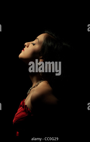 Beautiful woman in red dress standing in the dark