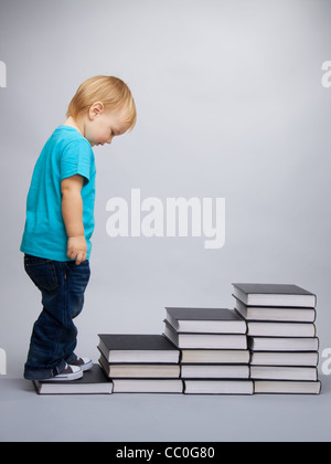 A kid begins his education represented as a steps made of books Stock Photo