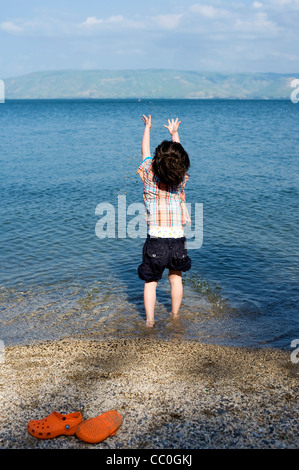 Boy throwing stones and playing in water in the Sea of Galilee, Kineret, Northern Israel Stock Photo