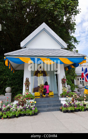 Woman kneels & prays at Buddhist shrine at the twin pagodas in Doi Inthanon National Park in northern Thailand Stock Photo