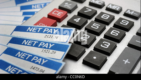 BRITISH PAYSLIPS SHOWING NET PAY AMOUNTS WITH CALCULATOR RE INCOMES WAGES SAVINGS COSTS OF LIVING RECESSION MORTGAGES PRICES  UK Stock Photo