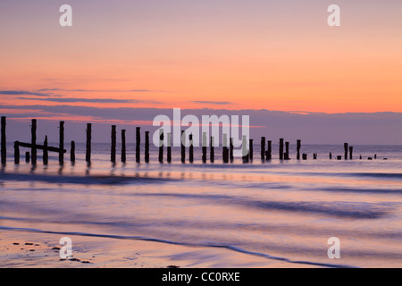 Old sea defences at dawn, smooth water from long exposure. Stock Photo
