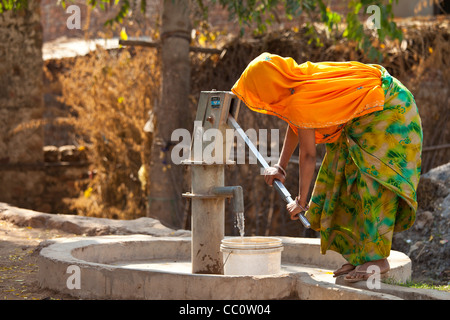 Indian woman villager pumping water from a well at Sawai Madhopur in Rajasthan, Northern India Stock Photo