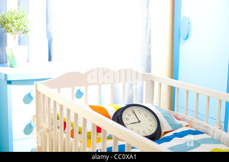 Nursery room with baby bed and clock counting time for new owner Stock Photo
