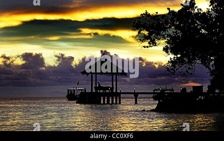 Person standing on a jetty in Silhouette against a sunset in the Maldives Stock Photo