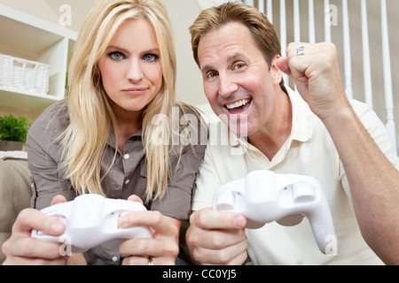 Young married couple, man and woman, having fun playing video console games together. Stock Photo