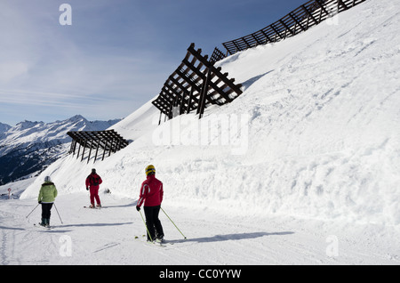 People skiing under snow control barriers above piste ski slope protecting skiers from avalanche risk in St Anton am Arlberg Tyrol Austria Stock Photo